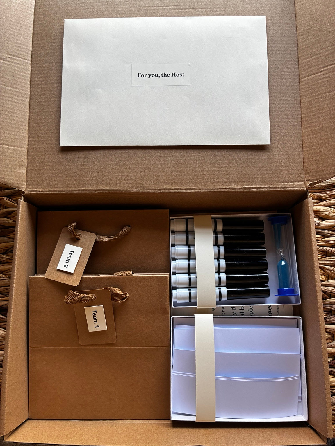 Open Charades Night Host Kit with two team bags, markers, a blue sand timer, paper slips and a host envelope