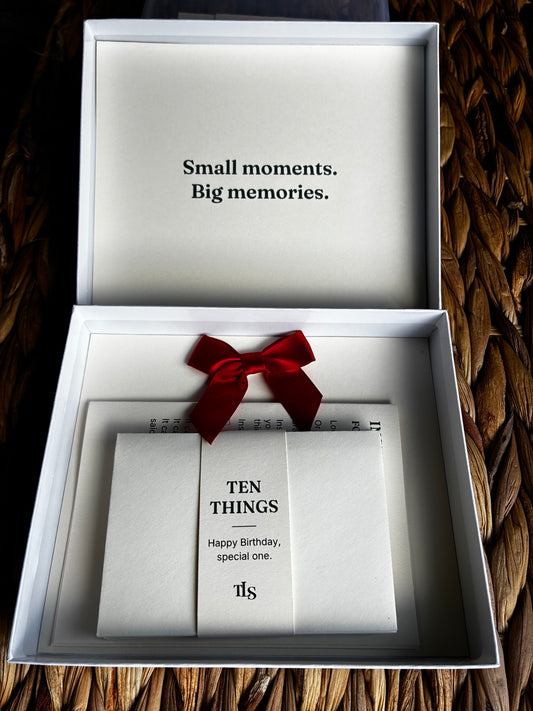 Open TEN THINGS birthday keepsake box with a bundle of envelopes, a printed insert and a red bow